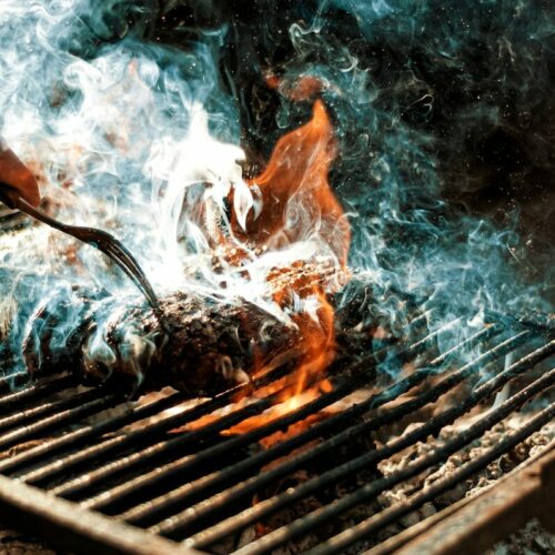 person cooking on grill with fire